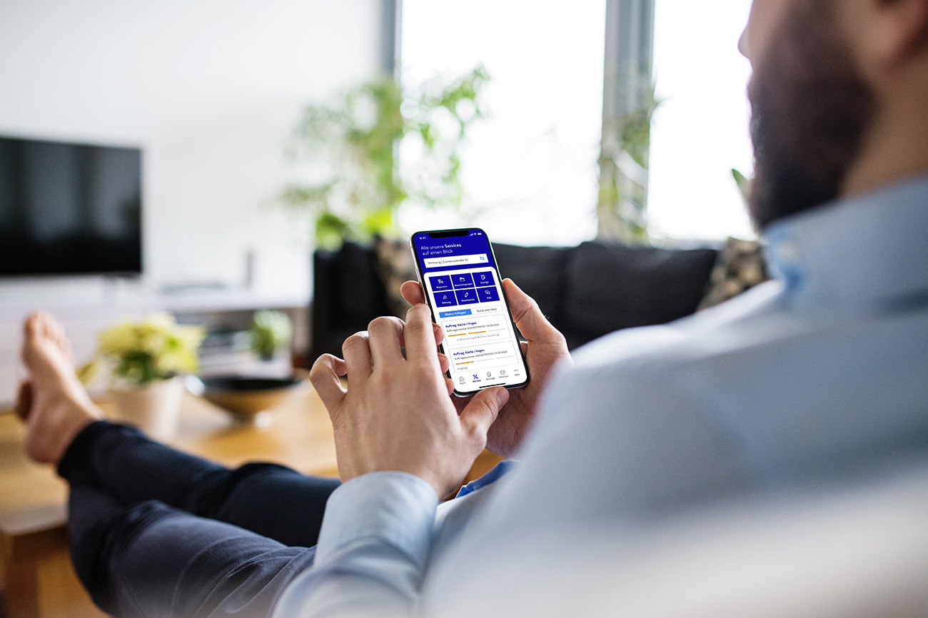 Ein Mann sitzt mit einem Smartphone in der Hand auf der Couch Ein Mann sitzt mit einem Smartphone in der Hand auf der Couch