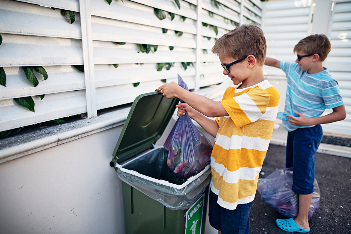 Little boys throwing out segregated trash to garbage bins